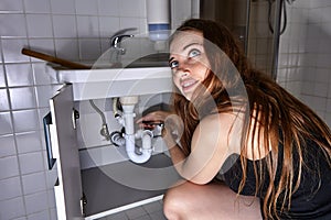 Woman wants to clean pipes in bathroom and disassembles siphon under sink.