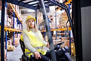 Woman warehouse worker with forklift.