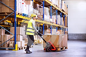 Woman warehouse worker with hand forklift truck.