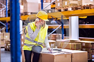 Woman warehouse worker with smartphone.