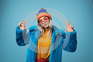 Woman in warm clothes gesturing at camera in studio