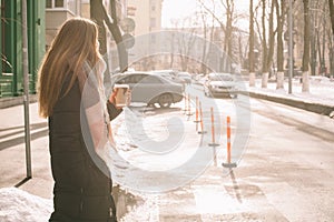 Woman with in warm clothing crossing city street in winter