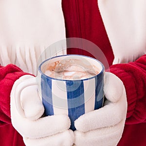 Woman in warm gloves holding cup of hot chocolate with marshmallows at winter