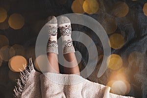Woman in warm socks on knitted blanket, top view. Space for text