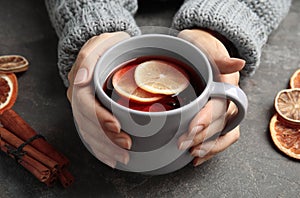 Woman in warm sweater with cup of hot winter drink at table