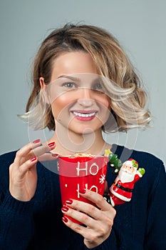 Woman in warm sweater is holding a cup of coffee.