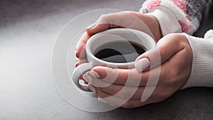 woman in warm sweater holds a white cup of coffee