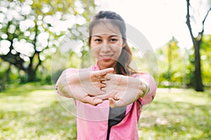 Woman warm up her body by stretching her arms to be ready for exercising and do yoga in the park.