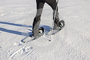 Woman in warm winter clothing snowshoeing