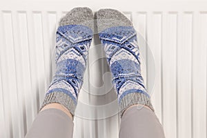 Woman warming feet near heating radiator, closeup
