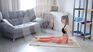 Woman warming feet practicing yoga doing exercises at home sitting on carpet.