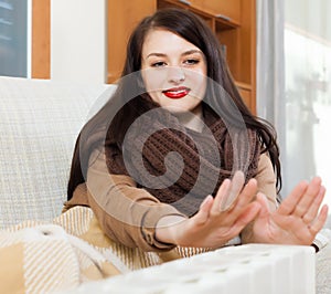 Woman warming hands near calorifer
