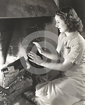 Woman warming her hands by the fireplace