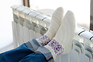 Woman warming up with feet on heater wearing woolen socks