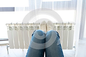 Woman warming up with feet on heater wearing woolen socks