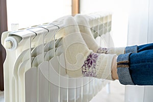 Woman warming up with feet on heater wearing woolen socks