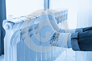 Woman warming up with feet on heater wearing woolen socks