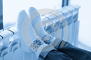 Woman warming up with feet on heater wearing woolen socks