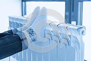 Woman warming up with feet on heater wearing woolen socks