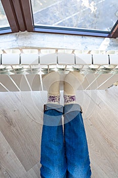 Woman warming up with feet on heater wearing woolen socks, view from above