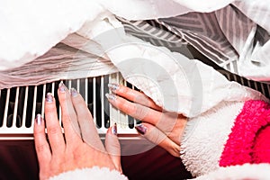 Woman warming up her hands on a white radiator