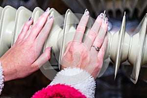 Woman warming up her hands on a white radiator