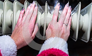 Woman warming up her hands on a white radiator