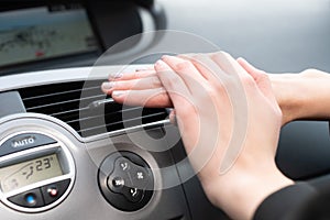 The woman warms her hands over the car& x27;s hot air outlet. Cold hands.