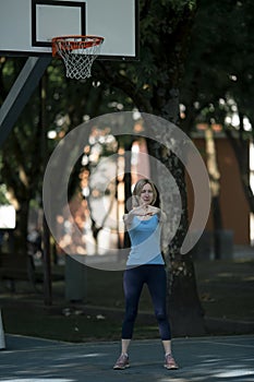 A woman warms up on an outdoor basketball court.