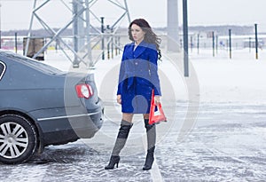 Woman with a warning sign on the road waiting for help