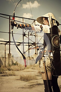 Woman warrior holding in her hands bow and arrow and arhering.