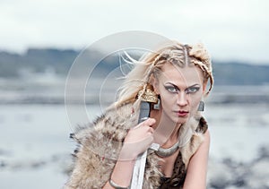 A woman is a warrior in a wolf`s skin with a sword in her hands. Girl of the Vikings. Reconstruction of the medieval scene.