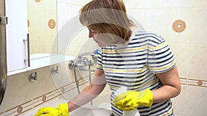 A woman washes the bathroom sink