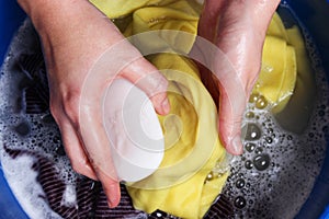 A woman washes clothes with her hands in soapy water. Hand wash clothes.