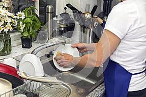 Woman washes dishes in the kitchen