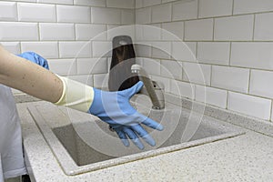 Woman washes dishes. Washing dishes - hands with gloves in kitchen, housework