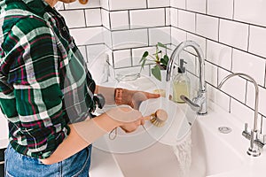 Woman washes dishes with a wooden eco brush