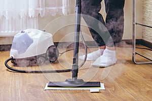 The woman washes the floor in the room with a white steam cleaner, a wet high-pressure steam. Cleaning of the apartment. we kill
