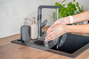 Woman washes hands and uses soap from reusable bottle. Eco-friendly lifestyle