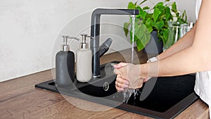 A woman washes hands and uses soap from reusable bottle. Eco-friendly lifestyle