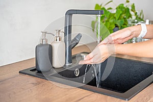 A woman washes hands and uses soap from reusable bottle. Eco-friendly lifestyle