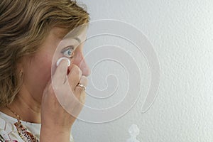 A woman washes off her makeup with a cotton swab