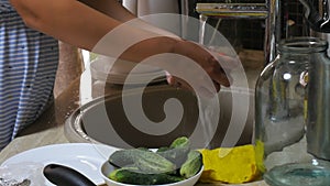 Woman washes tomatoes under a stream of water from a tap.