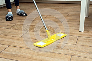 A woman washes underfloor heating in her house. A mop in the hands of a housekeeper