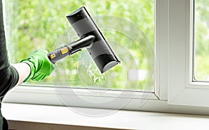 woman washes the windows of a house with a steam generator. To clean up the house in the spring. House cleaning.