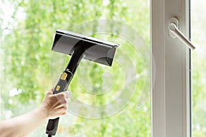 woman washes the windows of a house with a steam generator. To clean up the house in the spring. House cleaning.