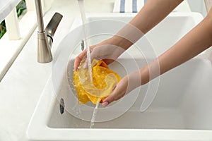 Woman washing beeswax food wrap under tap water in kitchen sink, closeup