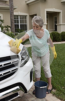 Woman washing the bodywork of a white saloon car