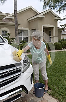 Woman washing the bonnet of a white saloon car