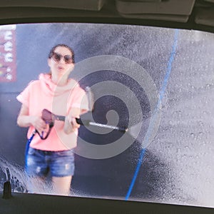 Woman washing car with pressure washer at self-service car wash station